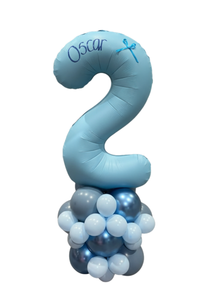 A number 2 balloon decoration for a second birthday, personalized with the name 'Oscar', mounted on a cluster of light blue, medium blue, and white balloons against a plain white background.