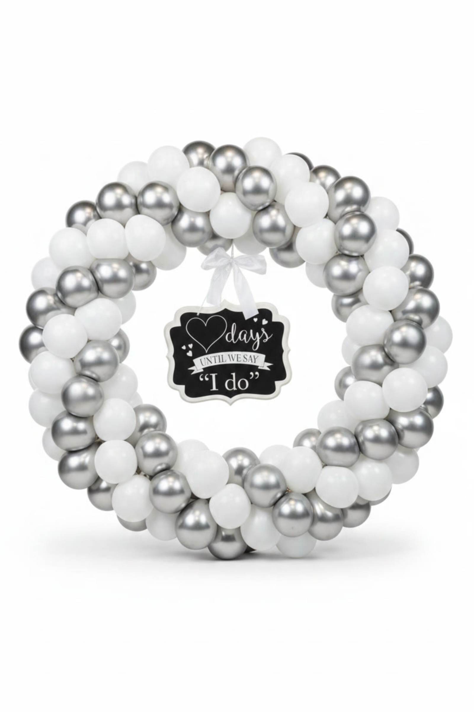 A balloon wreath made of white and silver balloons with a small black sign in the center that reads '(blank) days until we say "I Do"'